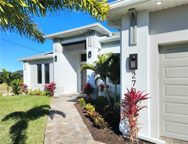 Doorway to property with stucco siding, a yard, and a garage