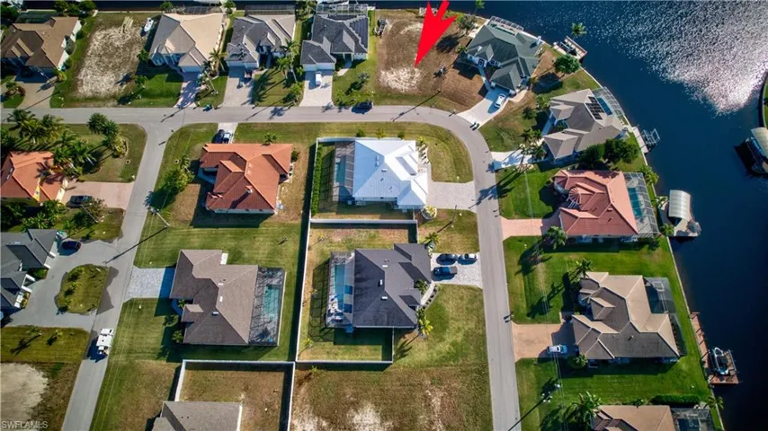 Aerial view of property and surrounding area featuring nearby suburban area and a large body of water