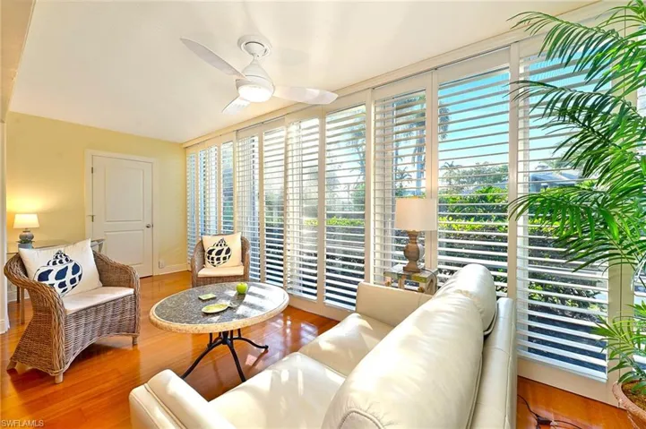 Living room with hardwood / wood-style floors, a wealth of natural light, expansive windows, and ceiling fan