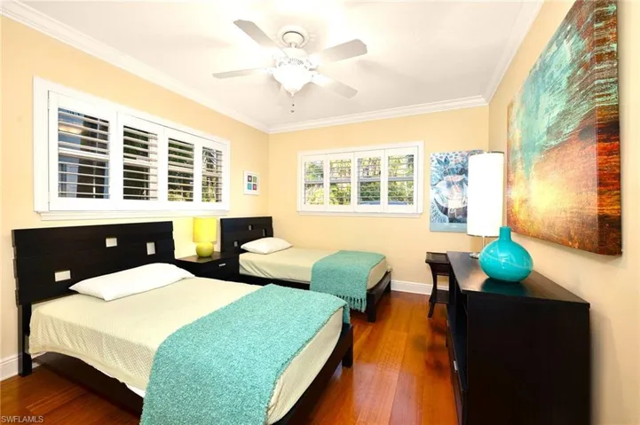 Bedroom with dark wood-type flooring, ornamental molding, and ceiling fan