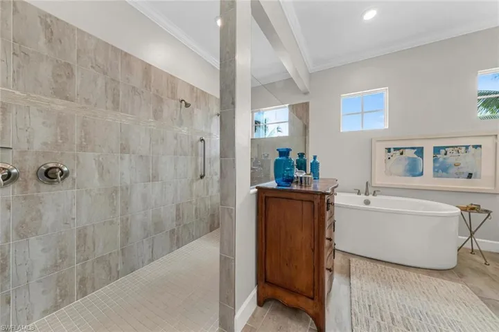 Palatial tiled shower with dual shower heads and hand rails.