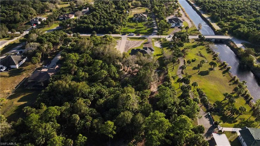 Aerial view of property and surrounding area with a forest and a nearby body of water