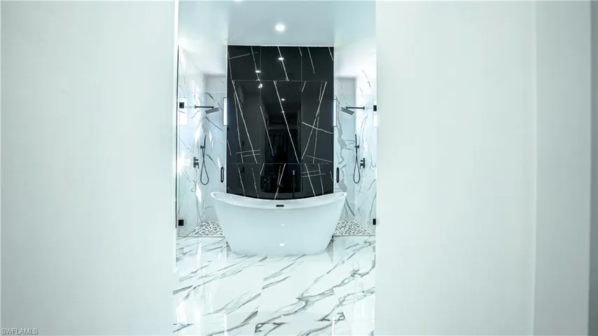 Bathroom view of a freestanding tub and a marble finish shower