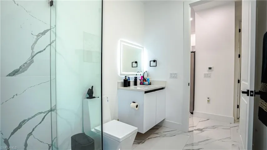 Bathroom with vanity, light marble finish flooring, and a marble finish shower