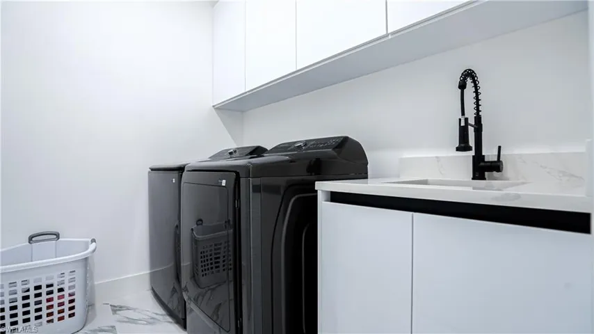Washroom featuring cabinet space, marble finish floors, and independent washer and dryer