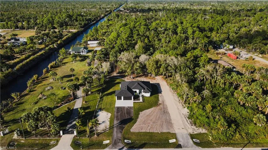 Aerial view of property and surrounding area with a heavily wooded area and a large body of water