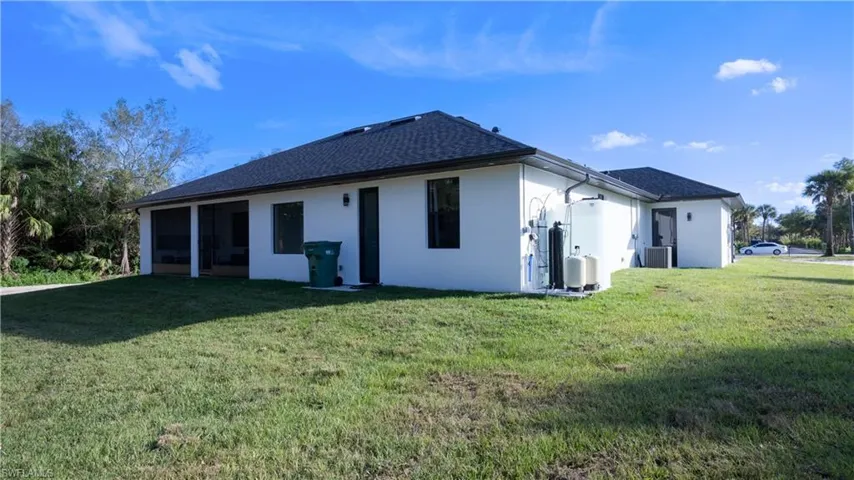 Rear view of property with a yard, roof with shingles, and stucco siding