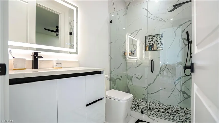 Bathroom featuring vanity and a marble finish shower