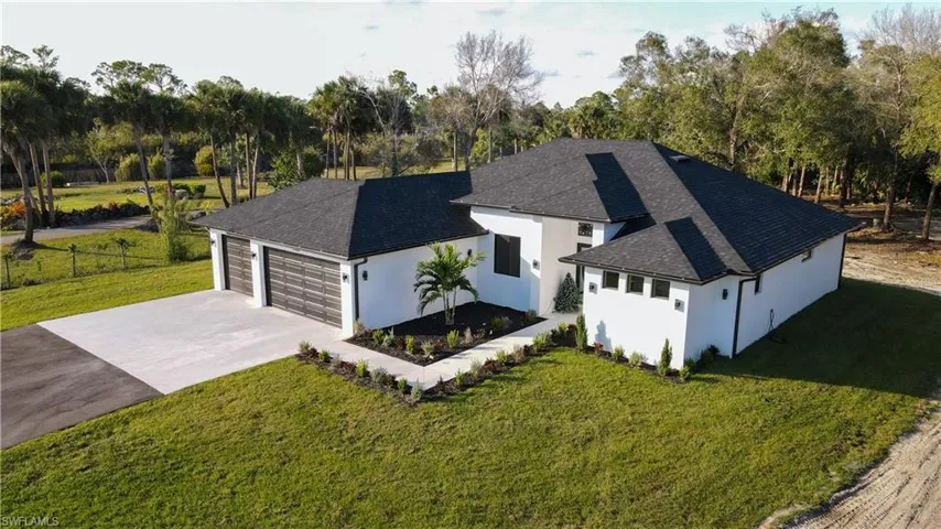 View of front of home with a shingled roof, a front yard, concrete driveway, stucco siding, and an attached garage
