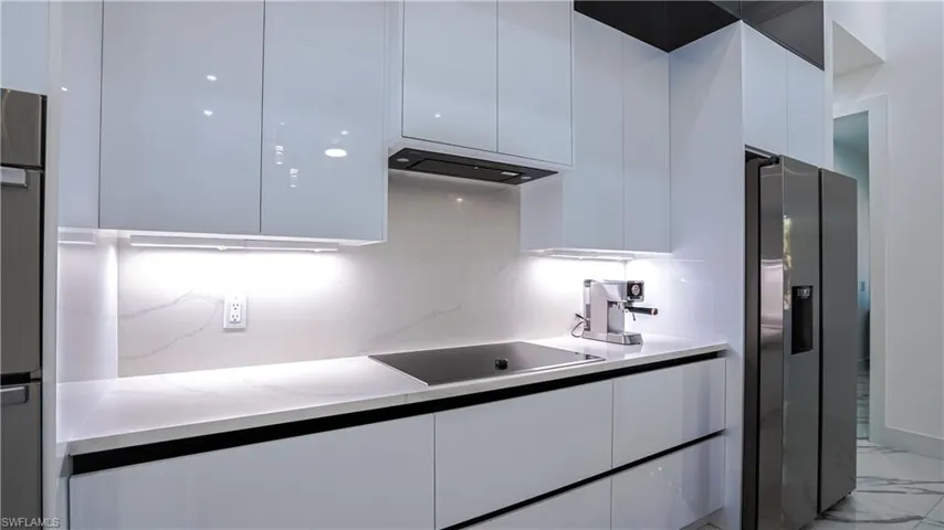 Kitchen featuring modern cabinets, white cabinetry, and appliances with stainless steel finishes