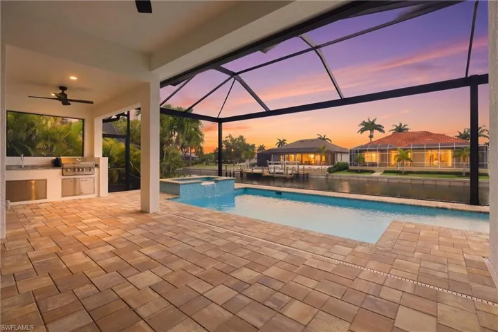 Combined pool / hot tub featuring area for grilling, a patio, glass enclosure, and a sunroom