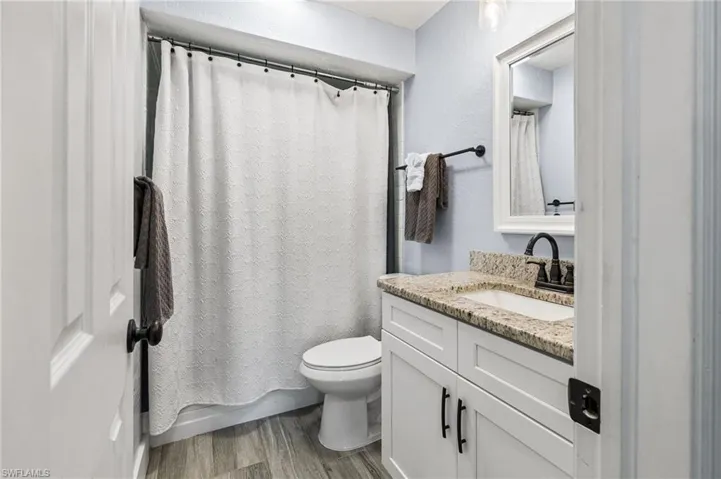 Bathroom with wood-type flooring, toilet, and vanity