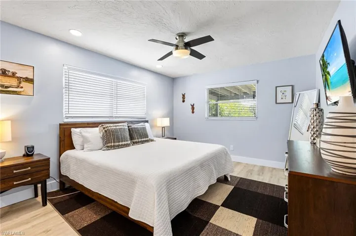 Bedroom with a textured ceiling, hardwood / wood-style flooring, and ceiling fan