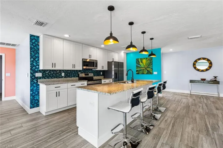Kitchen featuring a kitchen island with sink, white cabinetry, appliances with stainless steel finishes, and sink