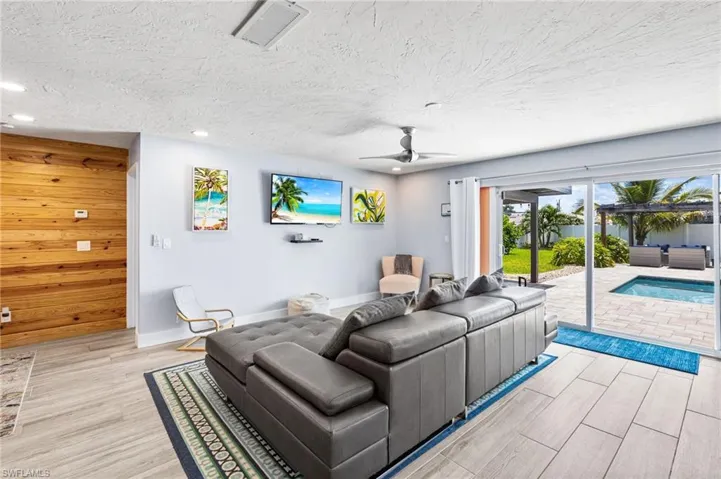 Living room featuring ceiling fan, wooden walls, light wood-type flooring, and a textured ceiling