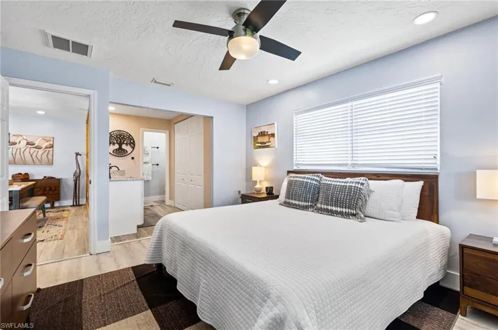 Bedroom featuring a textured ceiling, a closet, light wood-type flooring, and ceiling fan
