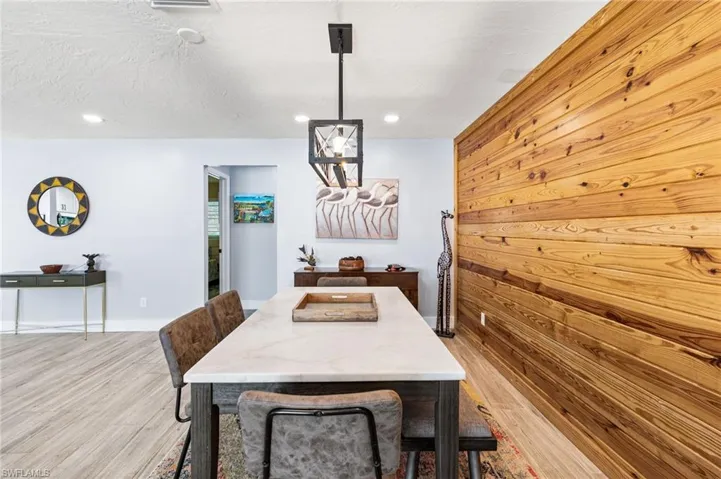 Dining room with wood walls, a textured ceiling, and light hardwood / wood-style floors