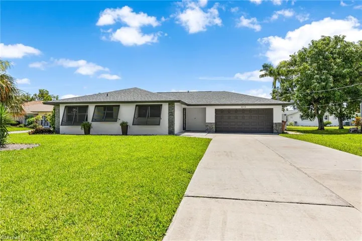 Single story home featuring a garage and a front lawn