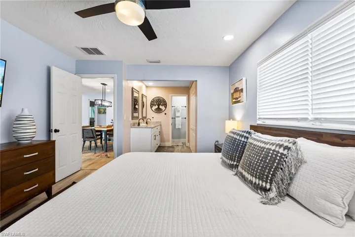 Bedroom with connected bathroom, ceiling fan, light wood-type flooring, sink, and a textured ceiling