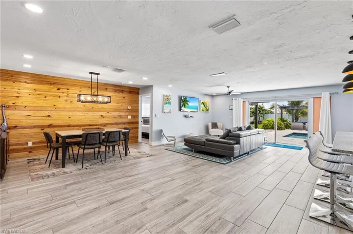 Living room featuring a textured ceiling, ceiling fan, and wooden walls