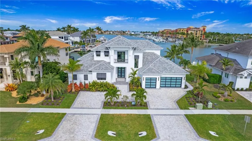 View of front of property featuring a water view, stucco siding, decorative driveway, and a front lawn