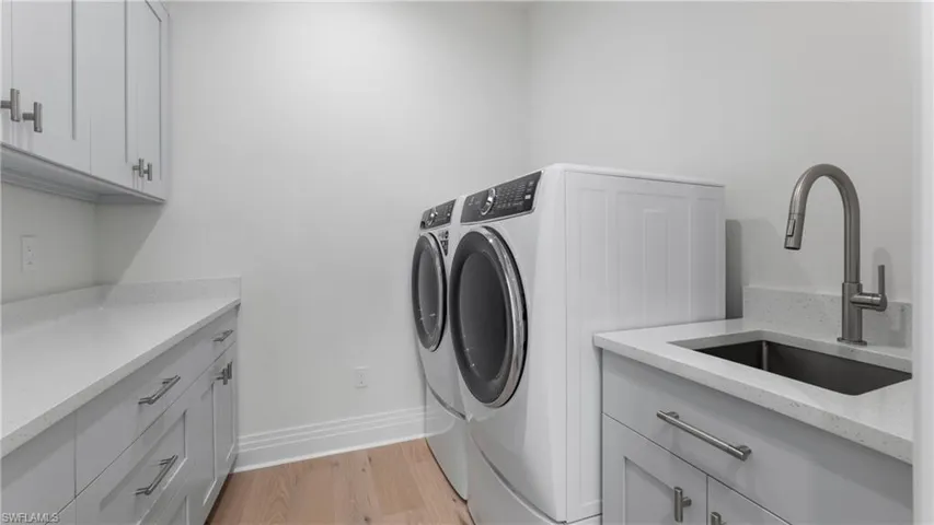 Laundry room with light wood-type flooring, independent washer and dryer, and cabinet space
