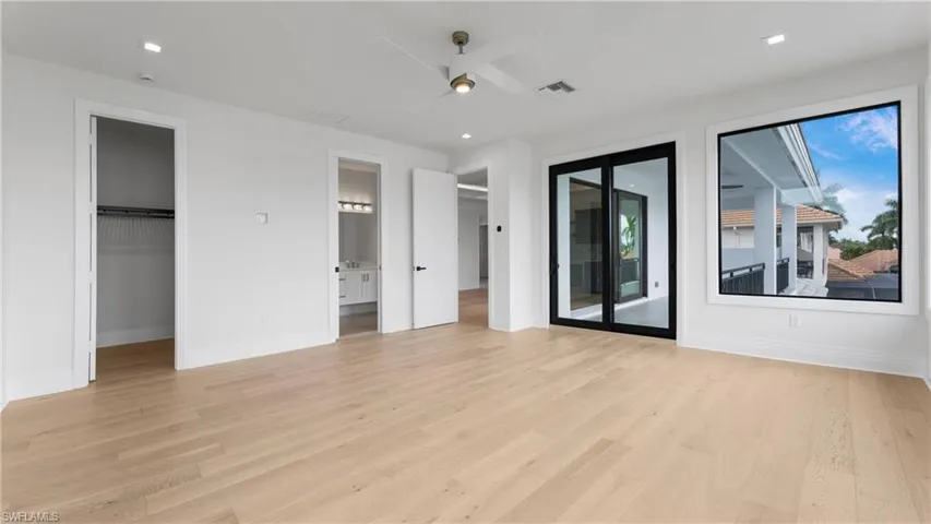 Unfurnished bedroom with a spacious closet, light wood-type flooring, ceiling fan, access to outside, and recessed lighting