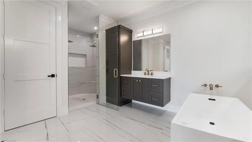 Bathroom with a soaking tub, vanity, and a marble finish shower