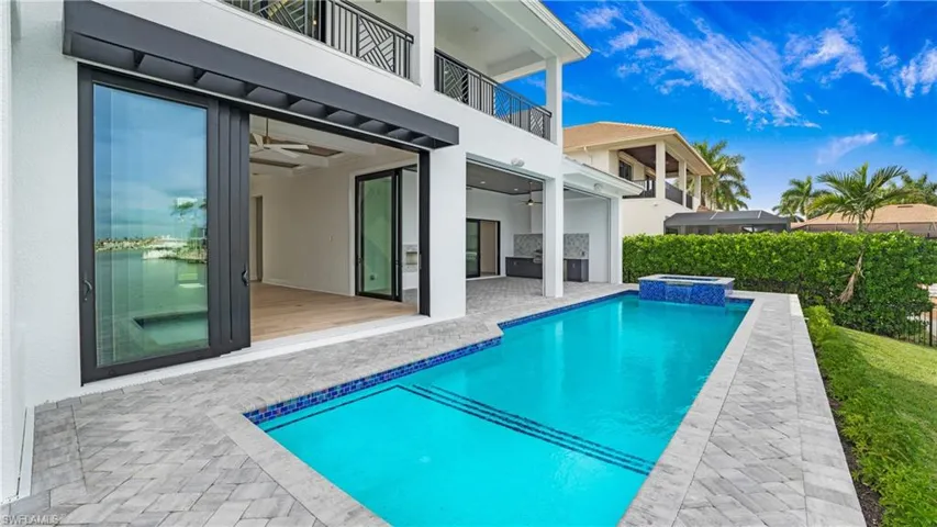 View of swimming pool featuring a patio area, a balcony, a pool with connected hot tub, and ceiling fan