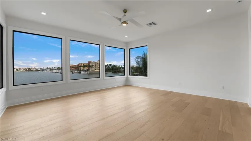 Empty room with light wood-style flooring, a ceiling fan, recessed lighting, and a water view