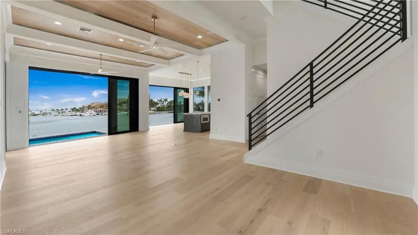 Unfurnished living room with beamed ceiling, light wood-type flooring, a ceiling fan, stairs, and recessed lighting