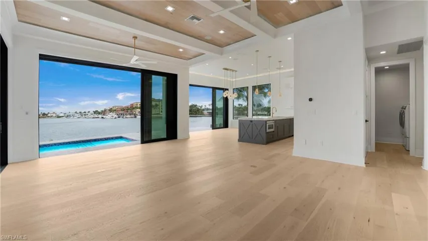 Empty room featuring light wood-style floors, a water view, a chandelier, recessed lighting, and wood ceiling