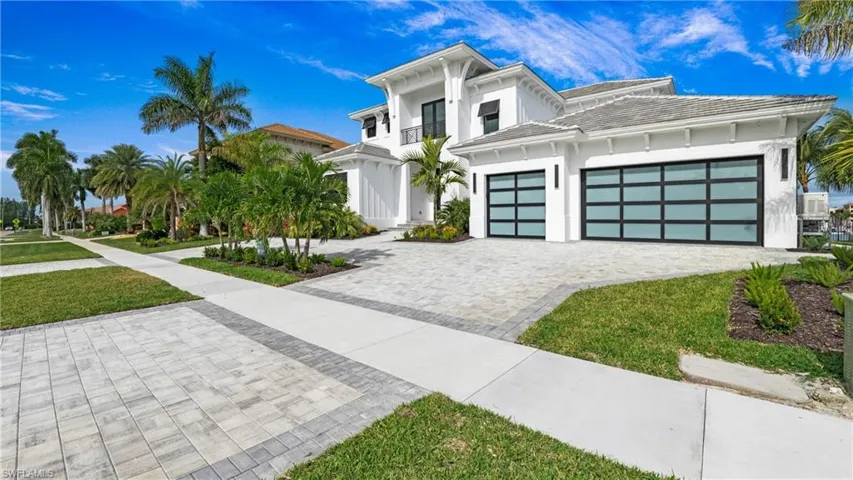 View of front of home with decorative driveway, a front yard, stucco siding, and a tiled roof