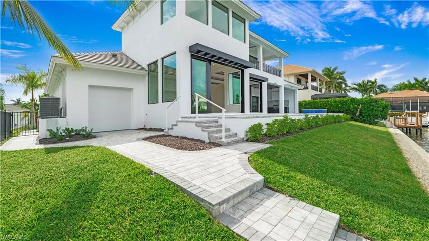 Back of property with a balcony, stucco siding, and a garage