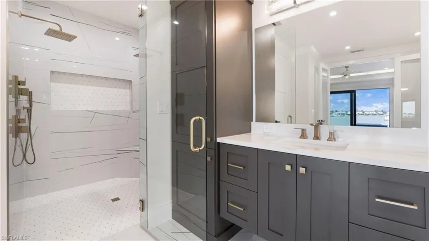 Full bath featuring vanity, a marble finish shower, and a ceiling fan