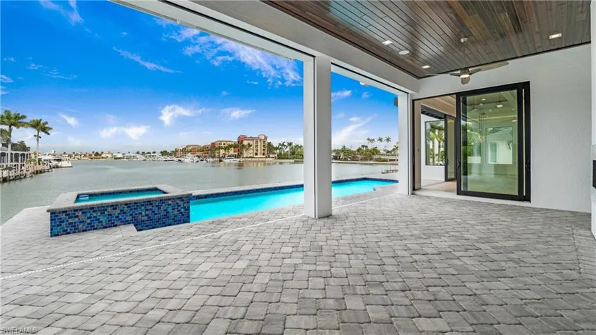 View of swimming pool with a patio area, a water view, and a pool with connected hot tub