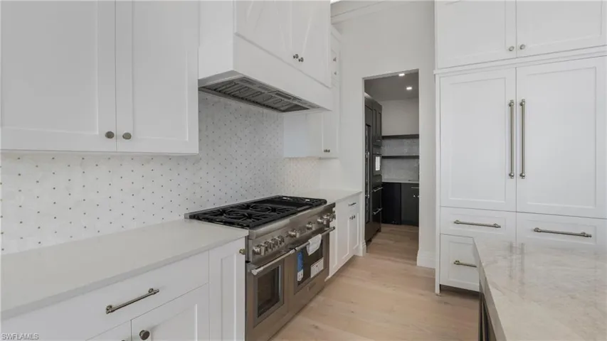 Kitchen with white cabinets, premium appliances, and light wood-style floors