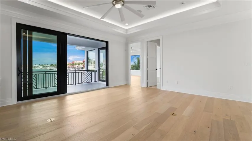 Spare room featuring wood finished floors, ceiling fan, a tray ceiling, ornamental molding, and recessed lighting