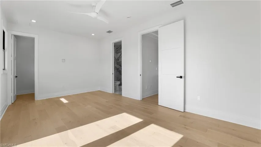 Unfurnished bedroom featuring light wood-style floors, recessed lighting, a ceiling fan, and ensuite bath