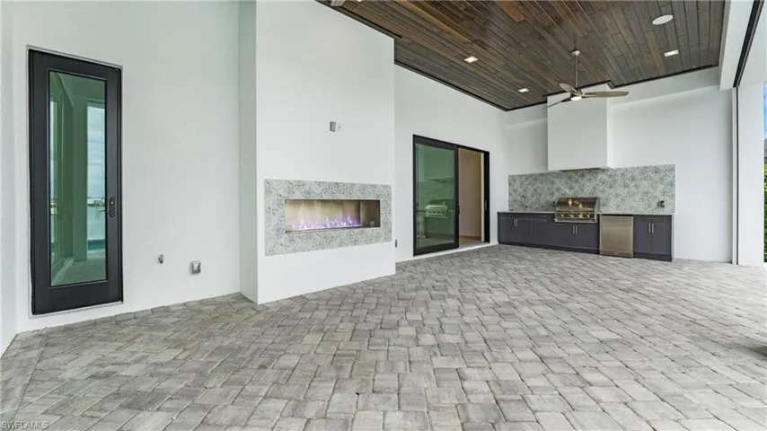 Unfurnished living room with wood ceiling, a warm lit fireplace, recessed lighting, a high ceiling, and ceiling fan