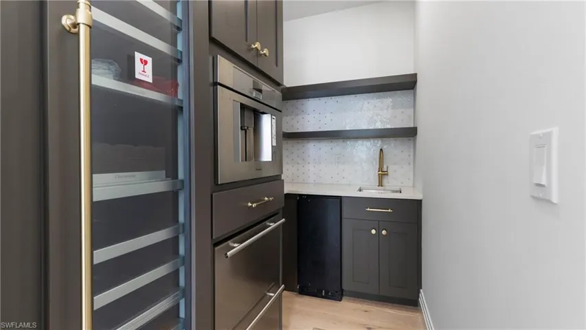 Kitchen featuring open shelves, light wood-type flooring, light stone counters, refrigerator, and decorative backsplash