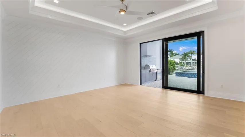 Spare room featuring light wood-type flooring, ceiling fan, and a raised ceiling