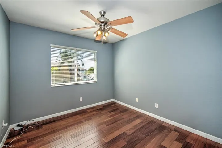 Spare room with dark wood-type flooring, ceiling fan, and baseboards