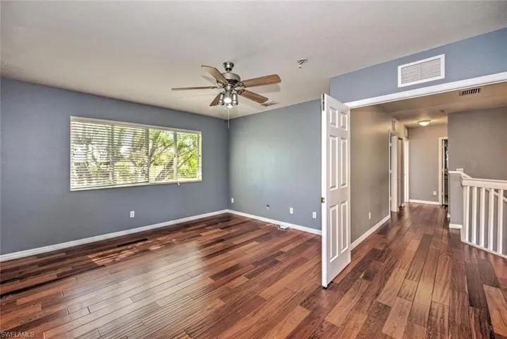 Spare room with wood finished floors, visible vents, and baseboards