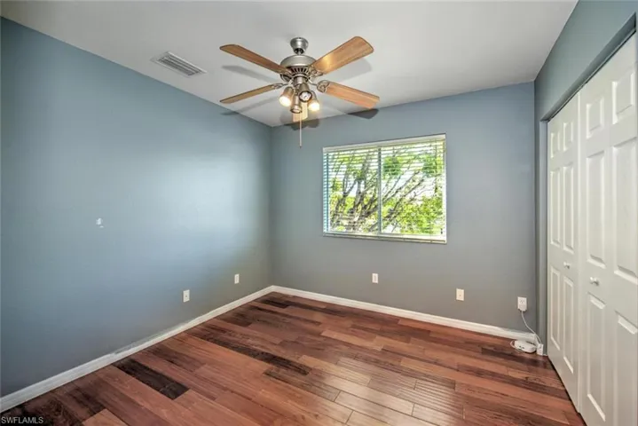 Unfurnished bedroom with baseboards, visible vents, ceiling fan, wood finished floors, and a closet