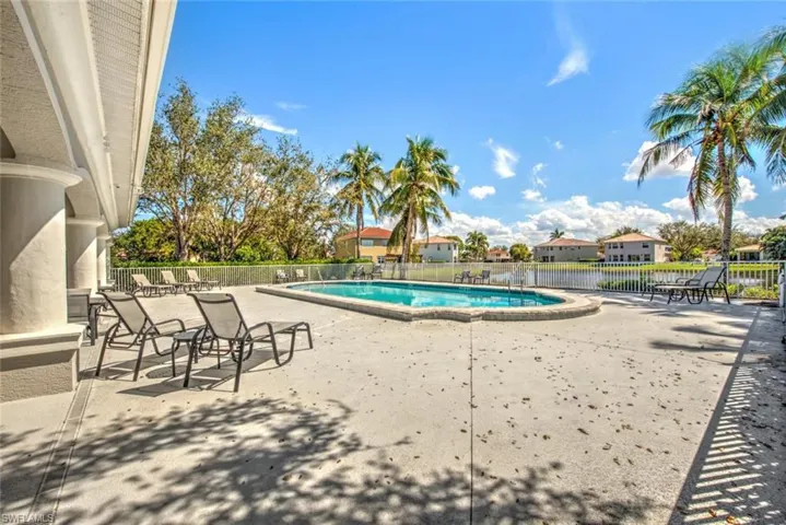 Community pool with a patio area and fence