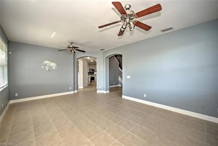 Spare room with arched walkways, ceiling fan, visible vents, and baseboards