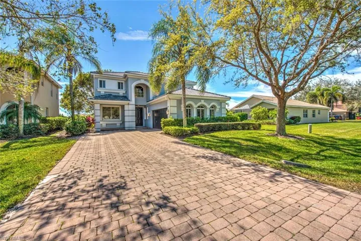 Mediterranean / spanish house with decorative driveway, stucco siding, a front yard, a garage, and a tiled roof