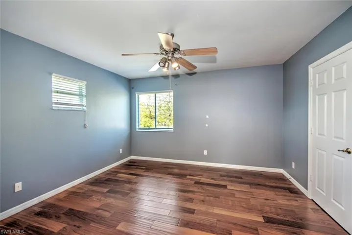 Spare room with a ceiling fan, dark wood-style flooring, and baseboards