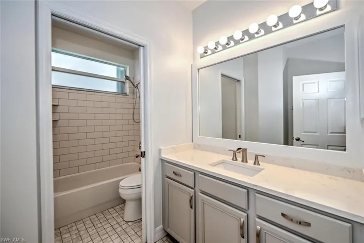 Full bath with shower / washtub combination, vanity, toilet, and tile patterned floors